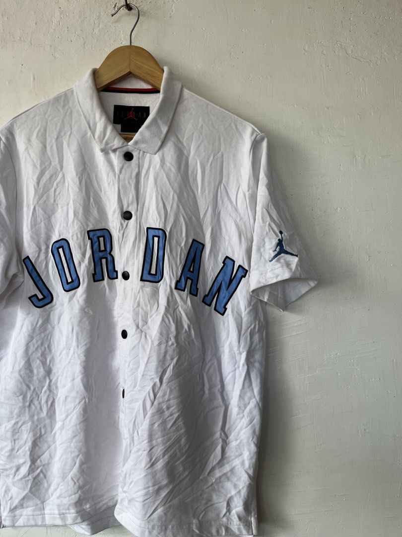 Jordan White Blue Button Polo Shirt Size L (Category: Tshirts & Polo Shirts ) located in Paranaque City. Submitted by commonfind.ph (Listing ID 1468938912, Image 2). Description: - Brand: Jordan -Size Large 23x27 - Item: Button-up polo shirt - Color: White with light blue chest lettering - Details: Embroidered Jumpman logo on left sleeve, black front buttons, and red collar trim - Size: L (Made in China) - Material: Comfortable cotton fabric - Co