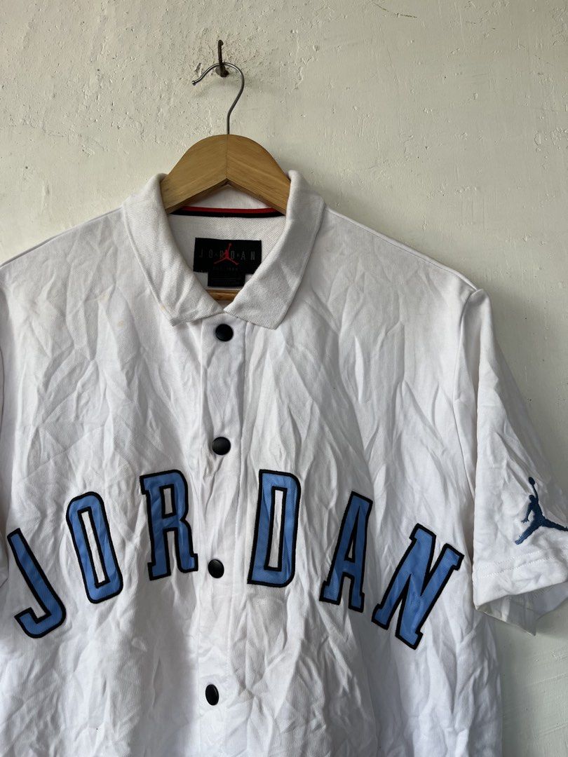 Jordan White Blue Button Polo Shirt Size L (Category: Tshirts & Polo Shirts ) located in Paranaque City. Submitted by commonfind.ph (Listing ID 1468938912, Image 3). Description: - Brand: Jordan -Size Large 23x27 - Item: Button-up polo shirt - Color: White with light blue chest lettering - Details: Embroidered Jumpman logo on left sleeve, black front buttons, and red collar trim - Size: L (Made in China) - Material: Comfortable cotton fabric - Co