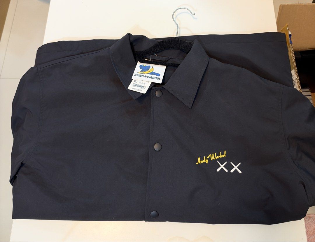 KAWS + Warhol Black Coach Jacket XL (Category: Coats, Jackets and Outerwear) located in Naic. Submitted by yozaktcg (Listing ID 1469008539, Image 1). Description: - Brand: KAWS + Warhol - Color: Black - Size: XL - Closure: Snap button front - Details: Yellow embroidered Andy Warhol signature with iconic white crossed eyes on the left chest - Condition: Brand new with original tag still attached to the collar.