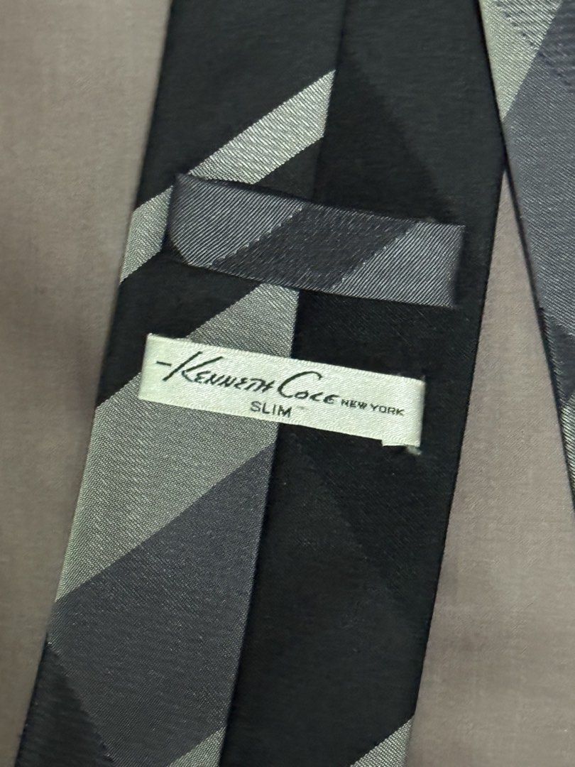 Kenneth Cole New York Slim Tie Black Grey Pattern (Category: Ties) located in Manila. Submitted by seangoart (Listing ID 1469048770, Image 3). Description: - Brand: Kenneth Cole New York - Design: Black and grey checkered pattern near the bottom, solid black top - Style: Modern slim cut - Condition: Clean fabric with tag clearly attached on the back - Versatility: Easy to match with a crisp white shirt and tailored suit for work or formal events.