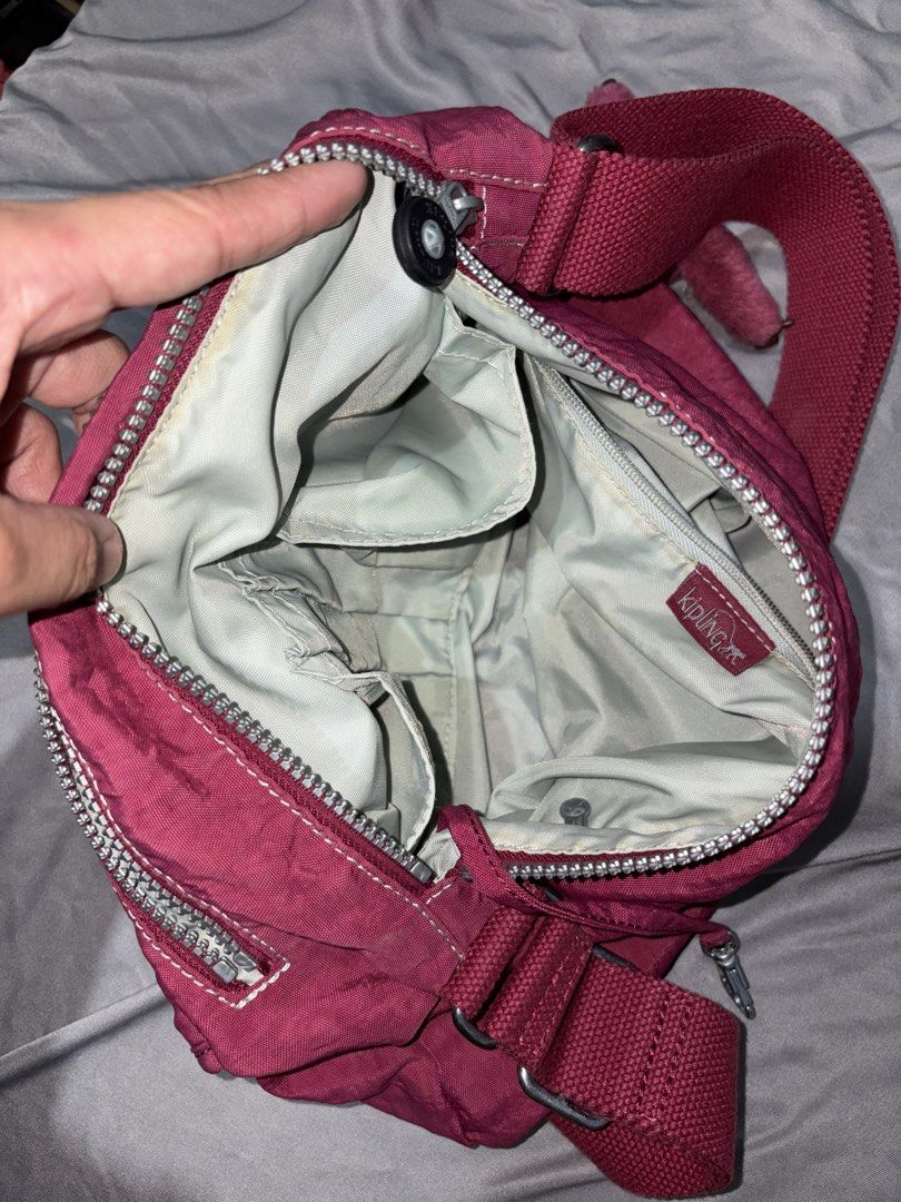Kipling Berry Red Shoulder Bag (Category: Shoulder Bags) located in Taguig. Submitted by aliuy (Listing ID 1469103060, Image 3). Description: - Authentic Kipling shoulder bag - Color: Vibrant Berry Red - Material: Signature durable crinkled nylon - Dimensions: Approx. 14.5in x 10in - Strap length: max length 48in, min length 26in - Compartments: Secure main zippered compartment and zippered front section - Pockets: Two Velcro front pockets, plus 