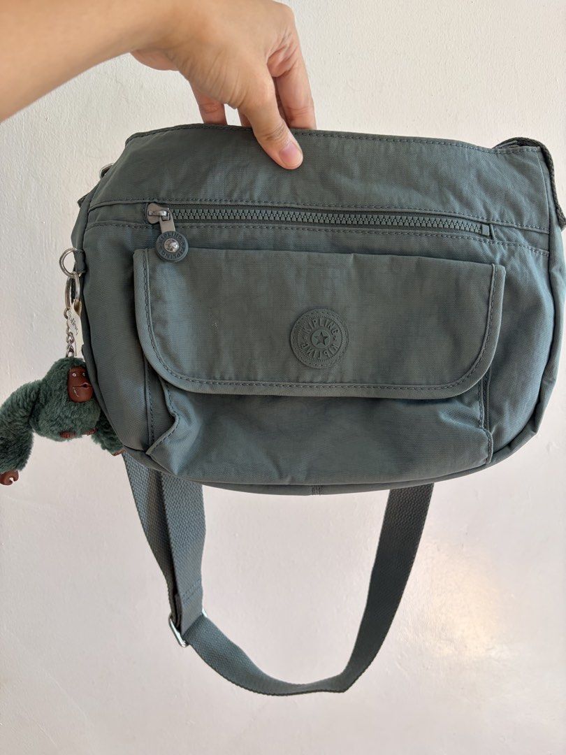 Kipling Grey Crossbody Bag with Monkey Keychain (Category: Cross-body Bags) located in Iloilo. Submitted by clariceanyanicole (Listing ID 1468933995, Image 1). Description: - Brand: Kipling Crossbody Bag - Color: Sage Grey - Material: Durable, lightweight nylon - Exterior: Zipped front pocket, flap pocket with signature round logo patch - Interior: Spacious main compartment with convenient slip pockets - Strap: Adjustable crossbody strap for cust
