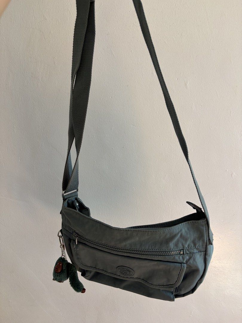 Kipling Grey Crossbody Bag with Monkey Keychain (Category: Cross-body Bags) located in Iloilo. Submitted by clariceanyanicole (Listing ID 1468933995, Image 2). Description: - Brand: Kipling Crossbody Bag - Color: Sage Grey - Material: Durable, lightweight nylon - Exterior: Zipped front pocket, flap pocket with signature round logo patch - Interior: Spacious main compartment with convenient slip pockets - Strap: Adjustable crossbody strap for cust