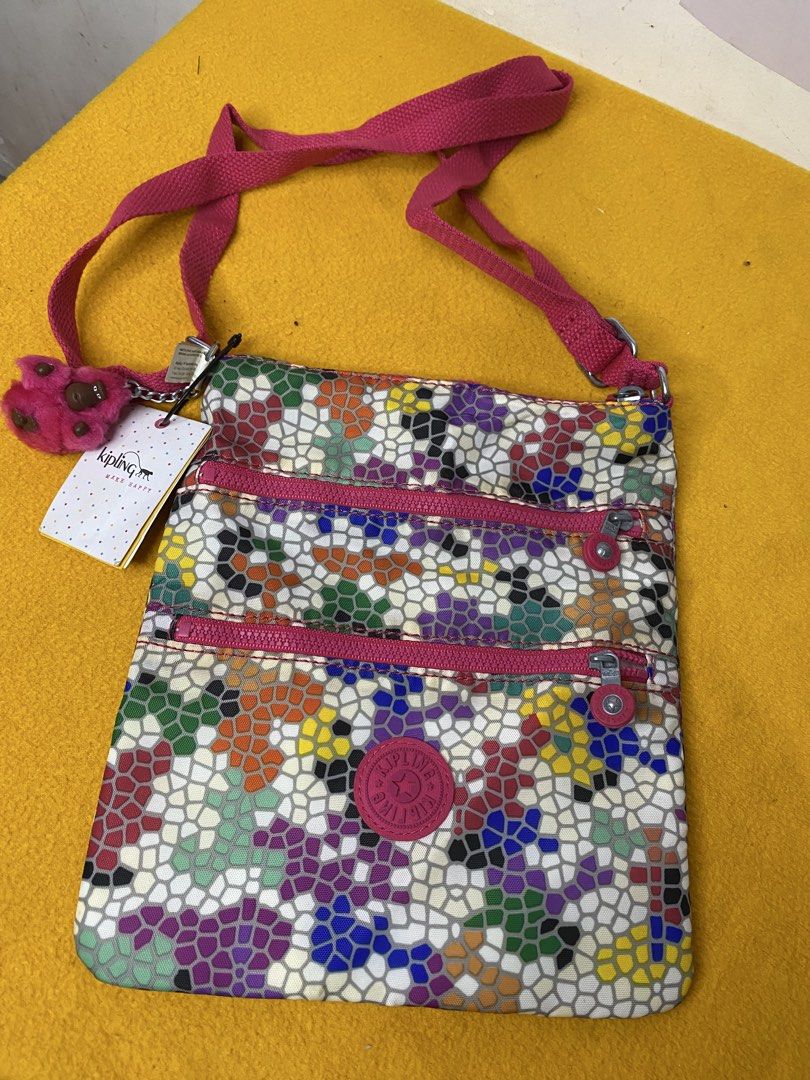 Kipling Keiko Spellbinder Multi-Colored Mosaic Crossbody Bag (Category: Cross-body Bags) located in Manila. Submitted by onfleekapparelph (Listing ID 1469067758, Image 2). Description: - Brand: Kipling Keiko Crossbody Bag - Print/Color: Spellbinder mosaic multi-colored pattern with a pink adjustable strap - Compartments: Secure top main zipper compartment and two handy front zip pockets - Interior: Clean white fabric lining - Extras: Includes ori