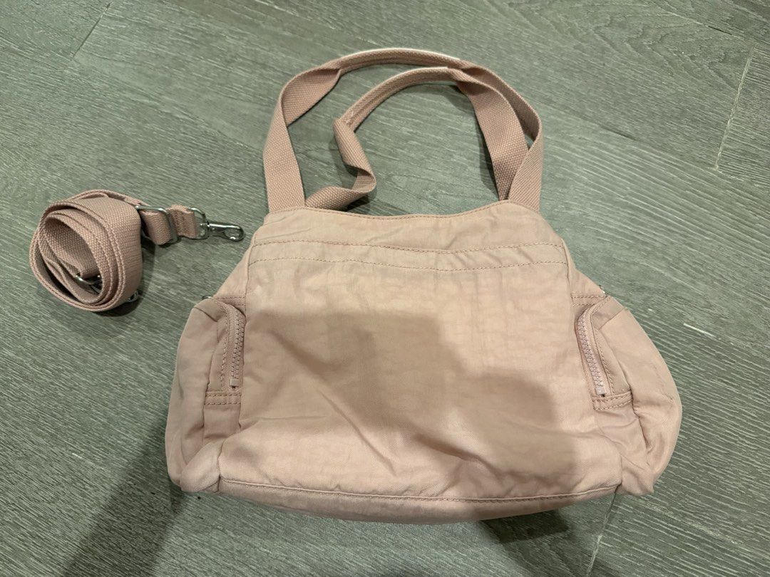 Kipling Pink Nylon Multi-Pocket Shoulder Bag with Strap (Category: Luxury Bags & Wallets) located in Manila. Submitted by pinkyclothes1267 (Listing ID 1469033556, Image 2). Description: - Brand: Kipling - Material: Durable nylon in a stylish pink shade - Versatile carry: Includes dual top handles and a detachable shoulder strap for shoulder or crossbody wear - Storage: Multiple exterior zip compartments on the front and sides - Interior: White fa
