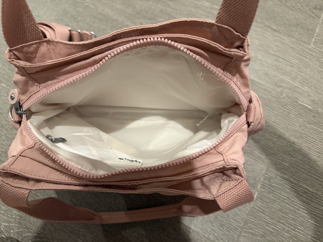 Kipling Pink Nylon Multi-Pocket Shoulder Bag with Strap (Category: Luxury Bags & Wallets) located in Manila. Submitted by pinkyclothes1267 (Listing ID 1469033556, Image 3). Description: - Brand: Kipling - Material: Durable nylon in a stylish pink shade - Versatile carry: Includes dual top handles and a detachable shoulder strap for shoulder or crossbody wear - Storage: Multiple exterior zip compartments on the front and sides - Interior: White fa