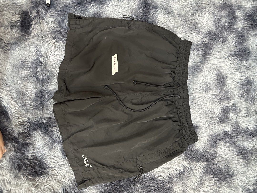 Kith Black Nylon Shorts (Category: Shorts) located in Quezon City. Submitted by nichole12 (Listing ID 1469089911, Image 1). Description: Black Kith nylon shorts with elastic waistband and adjustable drawstring. Embroidered white Kith logo near the lower left hem. Lightweight fabric with a relaxed fit. Size tag indicates waist fits 28 to 32. Great for casual everyday wear or workouts. Clean condition all around, no tears or stains..