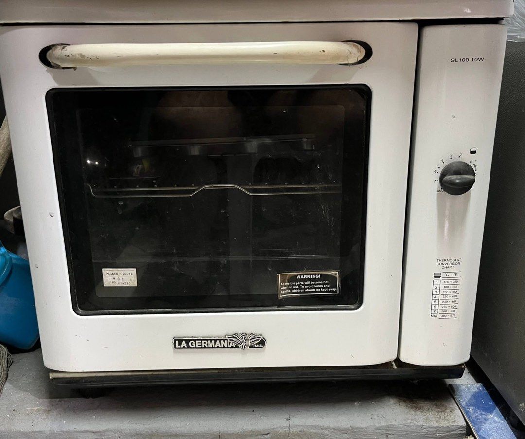 La Germania SL100 10W White Oven (Category: Ovens & Toasters) located in Manila. Submitted by lykaaaa2413 (Listing ID 1468969857, Image 1). Description: - Brand/Model: La Germania SL100 10W Oven - Color: Classic White - Design: Countertop oven with standard pull-down glass door and large white handle - Controls: Side control knobs with printed temperature conversion chart - Inclusions: Wire racks and baking trays - Condition: Working great, perfe