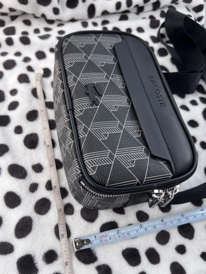 Lacoste Black Monogram Crossbody Bag (Category: Sling Bags) located in Rizal. Submitted by imallari88 (Listing ID 1469005990, Image 2). Description: - Authentic Lacoste crossbody bag in sleek black with a geometric monogram pattern - Durable PVC exterior with smooth black leather front trim and embossed branding - Eye-catching vibrant orange interior lining with multiple compartments and inner tag - Silver-tone metal zippers featuring iconic smal