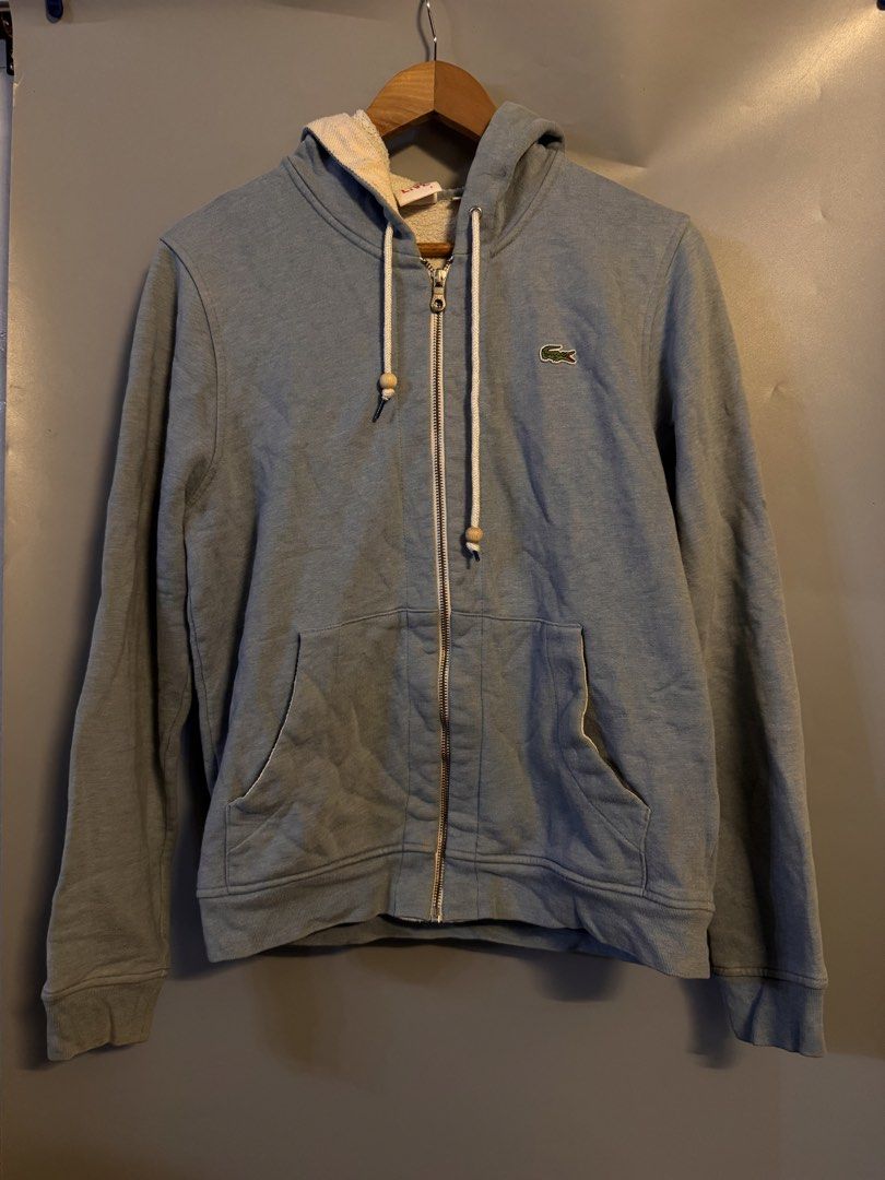 Lacoste Live Zip Hoodie Blue Size 4 (Category: Coats, Jackets and Outerwear) located in Alaminos. Submitted by outfitcheck.ph (Listing ID 1469100174, Image 1). Description: - Brand: Lacoste Live - Color: Dusty blue - Size: 4 (on collar tag) - Material: 80% cotton, 20% polyester blend - Lining: Cozy sherpa fleece for extra warmth - Details: Drawstrings with unique wooden bead ends, front split kangaroo pocket, ribbed cuffs and hem - Condition: Exc