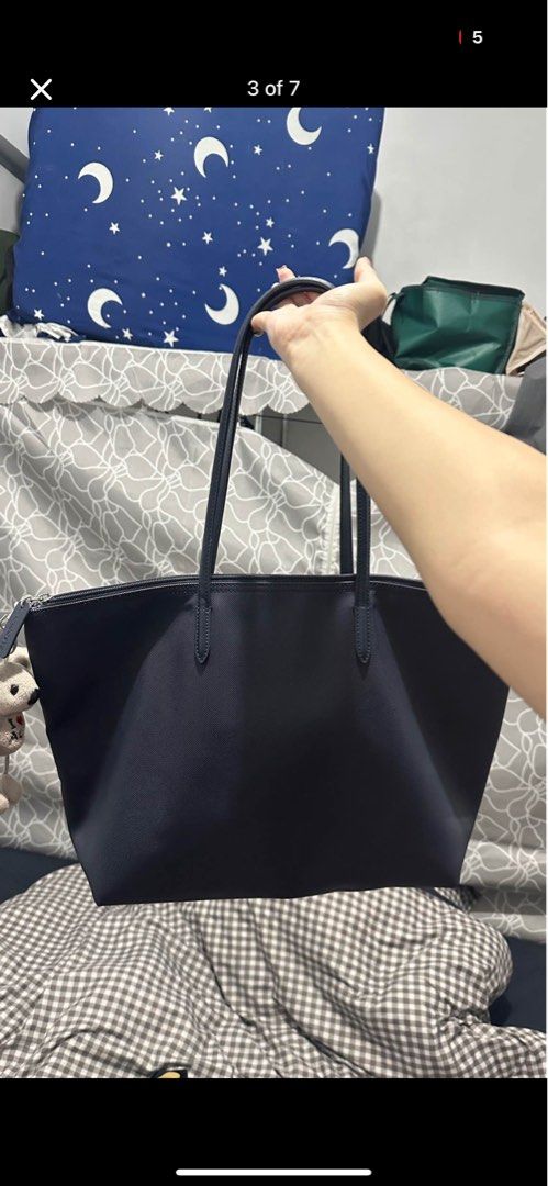 Lacoste Navy Blue Tote Bag (Category: Tote Bags) located in Manila. Submitted by safeocean.da498d (Listing ID 1468978262, Image 3). Description: - Brand: Lacoste - Color: Navy Blue - Design: Structured canvas texture with iconic green crocodile logo - Closure & Straps: Secure top zipper closure with double shoulder straps - Interior: Spacious main compartment with branded interior trim - Condition: Clean overall with minimal signs of use - Perfec