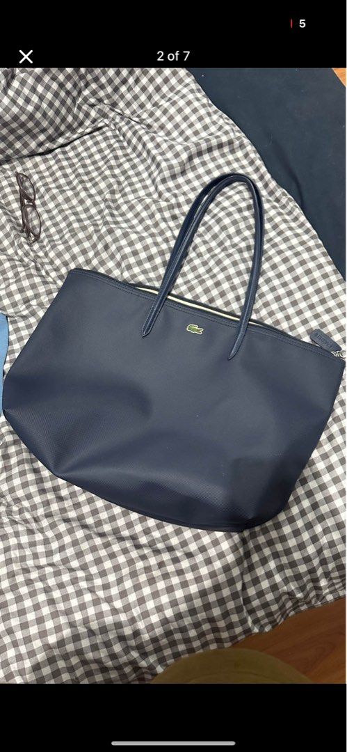 Lacoste Navy Blue Tote Bag (Category: Tote Bags) located in Manila. Submitted by safeocean.da498d (Listing ID 1468978262, Image 2). Description: - Brand: Lacoste - Color: Navy Blue - Design: Structured canvas texture with iconic green crocodile logo - Closure & Straps: Secure top zipper closure with double shoulder straps - Interior: Spacious main compartment with branded interior trim - Condition: Clean overall with minimal signs of use - Perfec