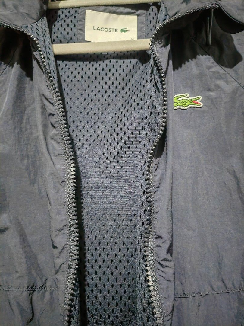 Lacoste Navy Blue Windbreaker Jacket Size 34 (Category: Coats, Jackets and Outerwear) located in Quezon City. Submitted by sashasarisarishoppe (Listing ID 1469012835, Image 3). Description: - Brand: Lacoste - Item: Lightweight Windbreaker Jacket - Color: Navy Blue - Size: 34 - Features: Full zip front, adjustable hood, mesh lining, two side zippered pockets, elasticated cuffs and hem, iconic embroidered green crocodile logo.