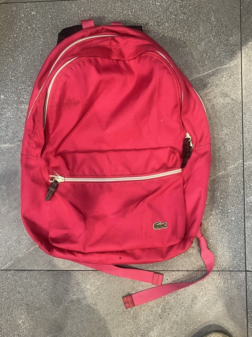 Lacoste Pink Backpack (Category: Backpacks) located in Manila. Submitted by cycy16_2004 (Listing ID 1468945353, Image 1). Description: - Brand: Lacoste - Color: Bright Pink - Material: 100% Polyester - Compartments: Main zip compartment and front zippered pocket - Interior: Branded leather patch and divider - Straps: Adjustable dark shoulder straps - Condition: Minor dark spots on the exterior fabric - Use: Perfect for school or everyday use.