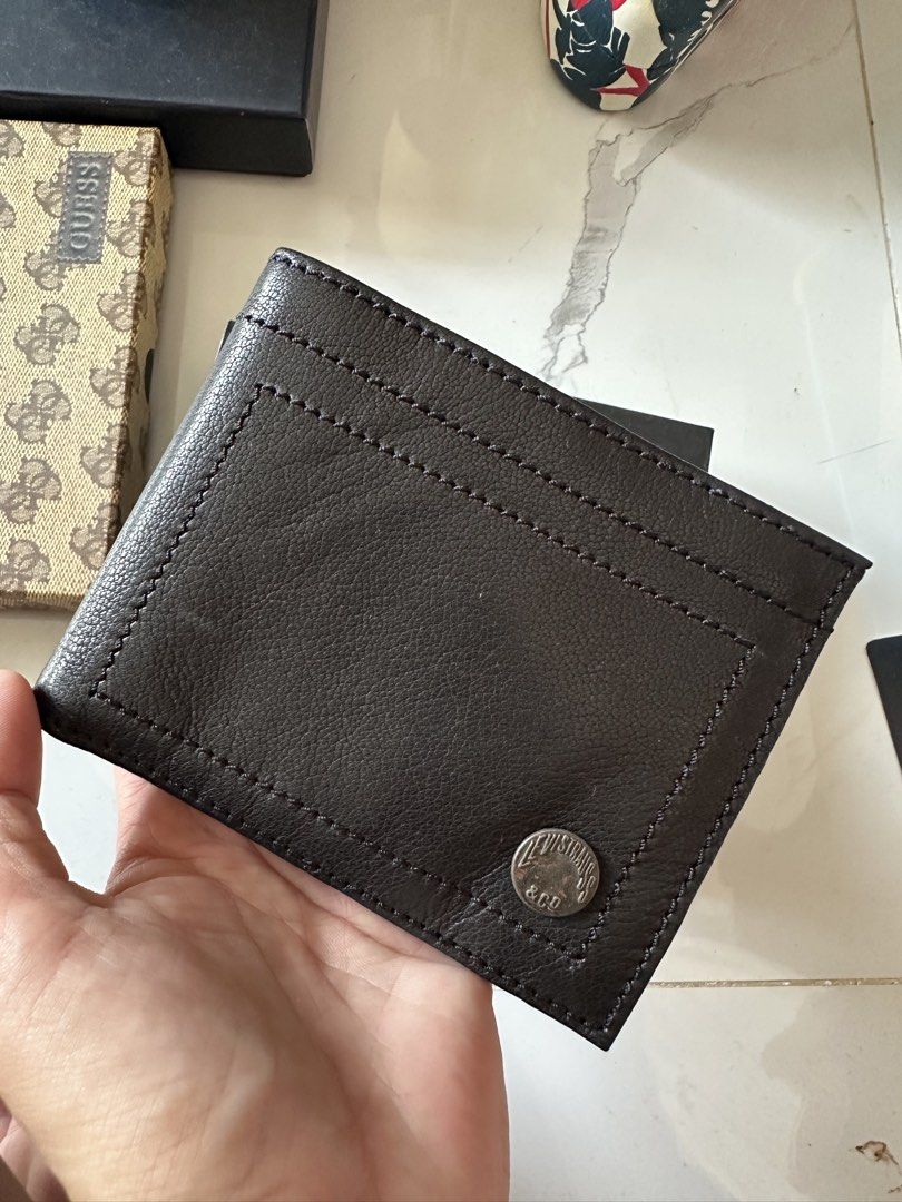 Levi's Leather Bifold Wallet (Category: Wallets & Card Holders) located in Vinzons. Submitted by melodylarg85741 (Listing ID 1468977741, Image 3). Description: Dark brown leather wallet from Levi's. Multiple card slots inside, plus a bill compartment. Metal logo button on the front. Clean interior lining with tag attached. Sturdy construction, classic design..