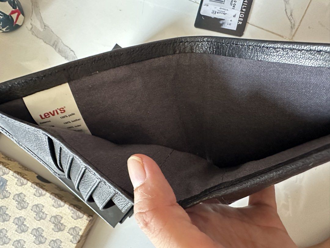 Levi's Leather Bifold Wallet (Category: Wallets & Card Holders) located in Vinzons. Submitted by melodylarg85741 (Listing ID 1468977741, Image 1). Description: Dark brown leather wallet from Levi's. Multiple card slots inside, plus a bill compartment. Metal logo button on the front. Clean interior lining with tag attached. Sturdy construction, classic design..