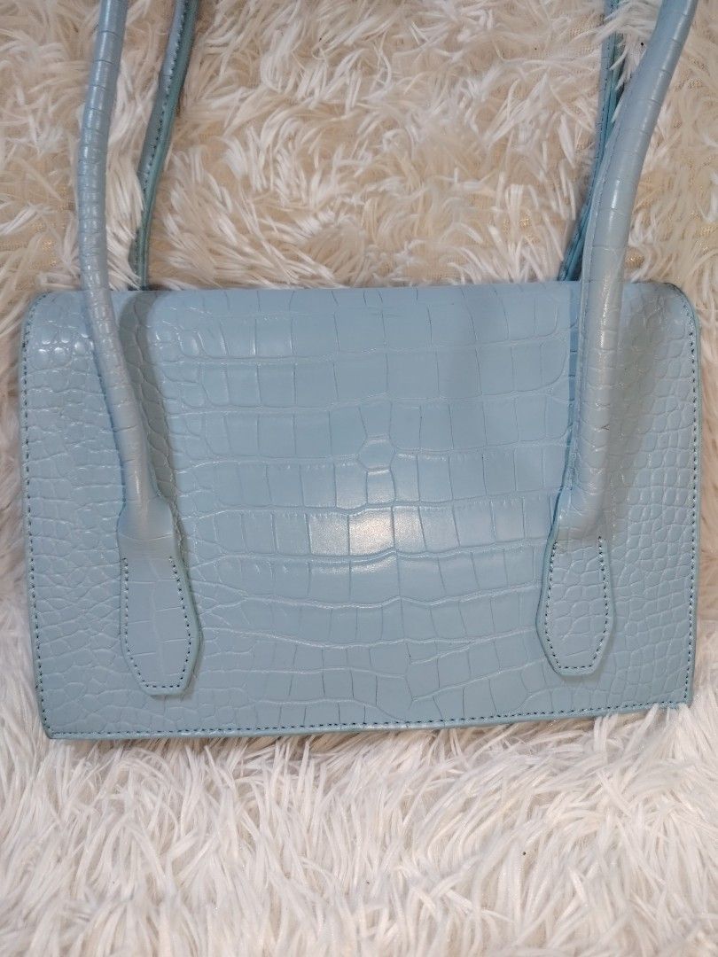 Light Blue Croc Embossed Shoulder Bag (Category: Shoulder Bags) located in Quezon City. Submitted by zhelcloset01 (Listing ID 1469063598, Image 2). Description: - Color: Light blue - Material/Texture: Trendy all-over croc-embossed design - Closure: Secure front flap with a magnetic snap button - Straps: Comfortable double shoulder straps - Interior: Clean lining with a handy zippered divider pocket - Capacity: Very spacious and ideal for daily es