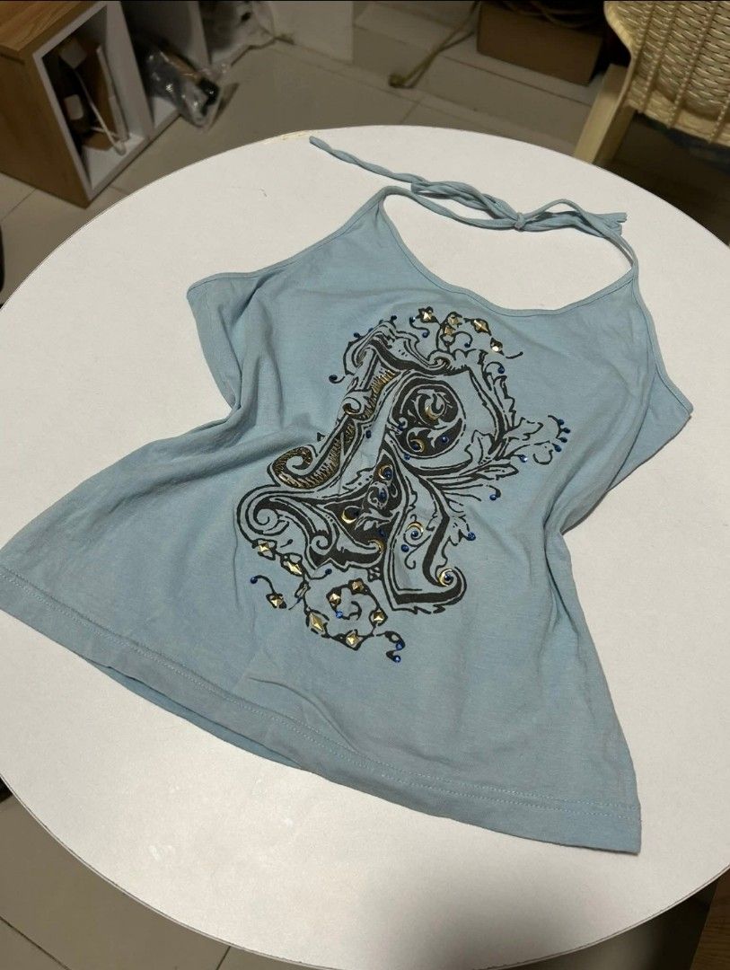 Light blue halter top (Category: Sleeveless) located in Makati City. Submitted by galaxyjaykim (Listing ID 1469072286, Image 1). Description: - Color: Light blue - Material: Soft cotton fabric - Design: Vintage-style graphic print with stud and blue rhinestone details - Fit: Comfortable, ties at the neck - Style: Casual, great for warm weather or layering.