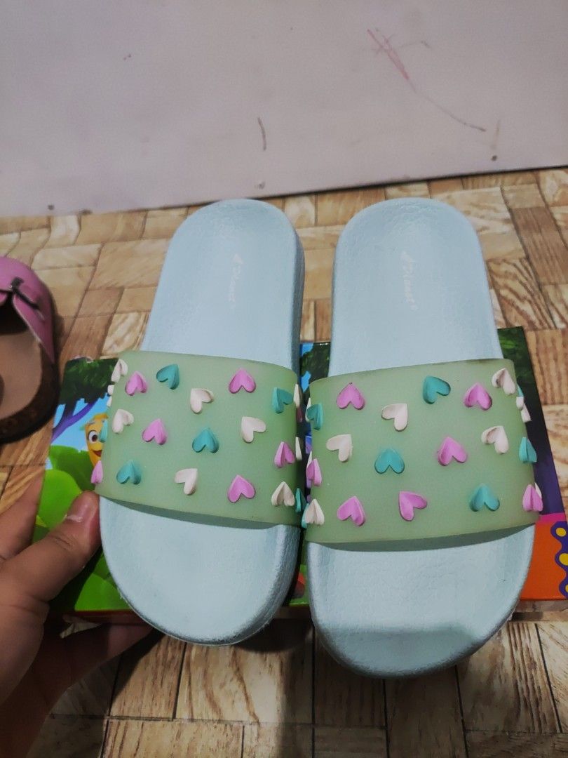 Light Blue Heart Pattern Slide Sandals Slippers (Category: Slippers and slides) located in Paranaque City. Submitted by jtaguirre (Listing ID 1468934390, Image 1). Description: - Color: Light blue with colorful heart charms - Style: Casual slip-on sandals - Features: Textured footbed for grip and zig-zag patterned rubber sole - Condition: Clean overall, minor dirt on soles from handling - Usage: Perfect for indoors or outdoors.