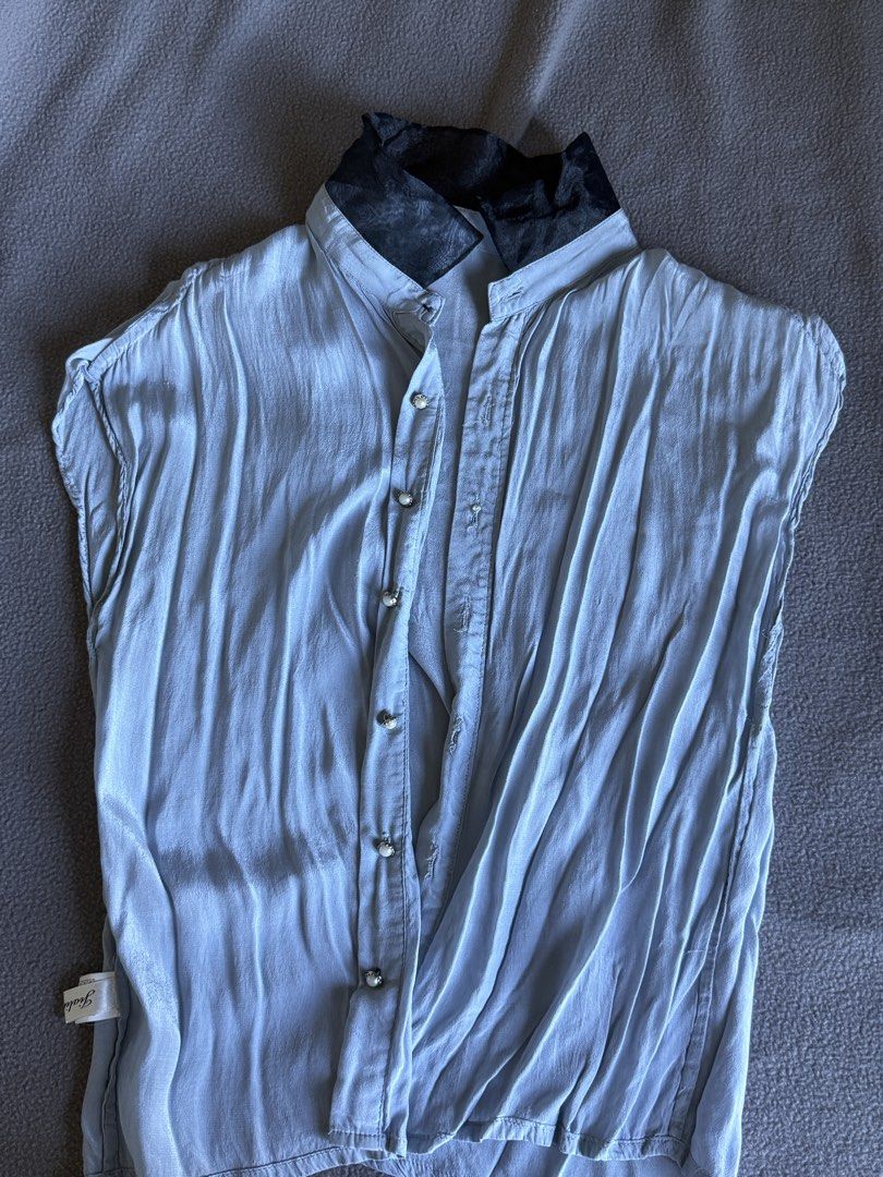 Light blue sleeveless button-up blouse with black contrasting collar (Category: Blouses) located in Pasig City. Submitted by laagn.ph (Listing ID 1469088993, Image 2). Description: - Color: Light blue with contrasting black patterned collar - Design: Sleeveless, button-up front with elegant pearl-style buttons - Fit: Relaxed, draped fit through the body - Fabric: Lightweight with a slight sheen - Styling: Ideal with high-waisted skirts or trouser