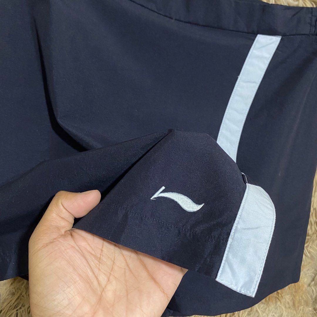 Li-Ning Navy Blue Skort Size L (Category: Skirts) located in Butuan. Submitted by jc13thrifts (Listing ID 1469060334, Image 2). Description: - Brand: Li-Ning - Color: Navy blue with contrast light blue vertical stripe and logo - Size: L - Features: Built-in shorts underneath for active movement, elastic waistband at the back with button and zip closure, and a back pocket with button detail - Condition: Excellent.