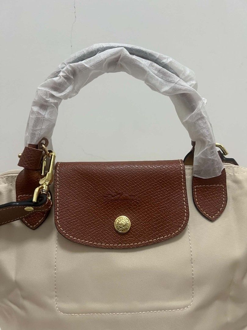 Longchamp Le Pliage Small Crossbody Bag Paper (Category: Purses & Pouches) located in Paoay. Submitted by rvf1230 (Listing ID 1468932401, Image 3). Description: - Brand: Longchamp Le Pliage - Color: paper color leather flap, handles, and strap - Condition: Brand new, handles still wrapped in protective paper - Hardware: Gold-tone with iconic horse logo zipper pull - Features: Adjustable shoulder/crossbody strap, structured design, front pocket, a