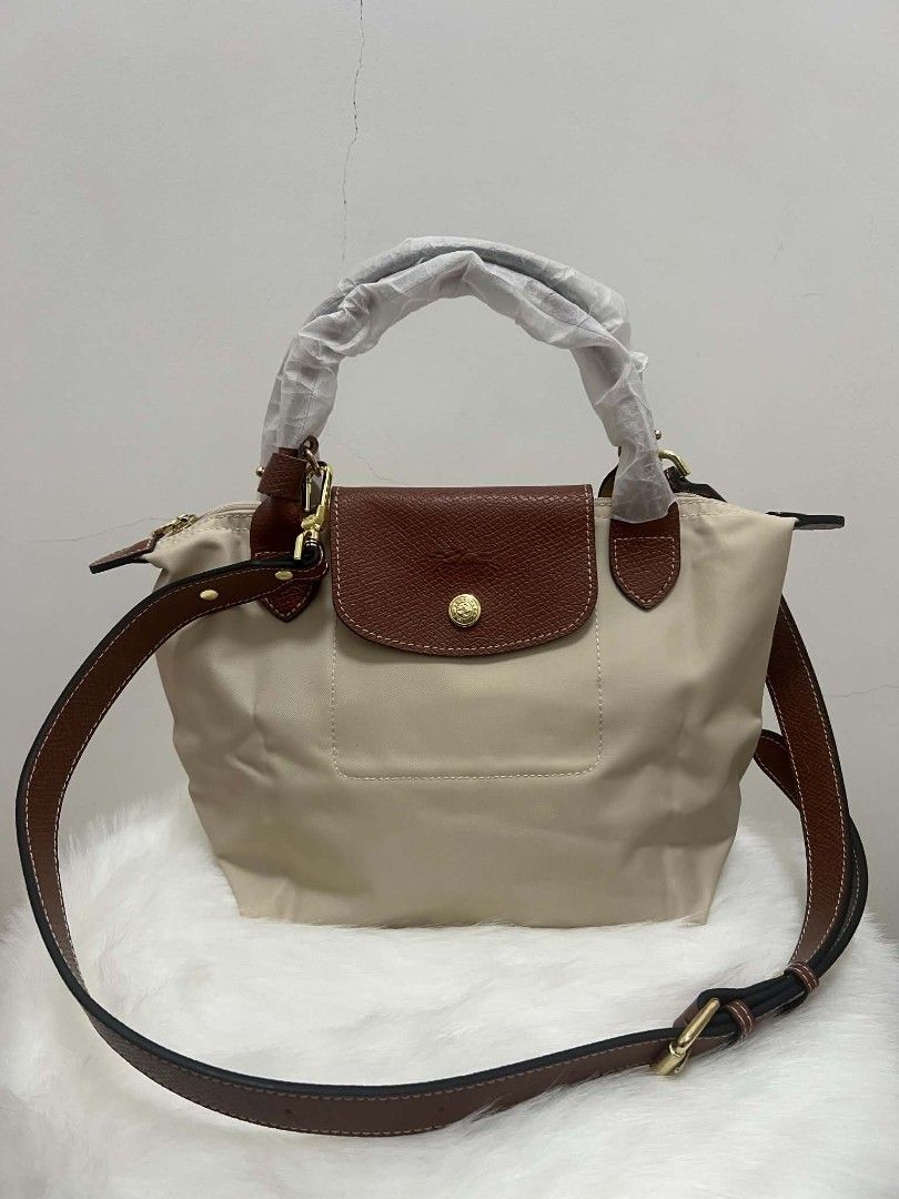 Longchamp Le Pliage Small Crossbody Bag Paper (Category: Purses & Pouches) located in Paoay. Submitted by rvf1230 (Listing ID 1468932401, Image 2). Description: - Brand: Longchamp Le Pliage - Color: paper color leather flap, handles, and strap - Condition: Brand new, handles still wrapped in protective paper - Hardware: Gold-tone with iconic horse logo zipper pull - Features: Adjustable shoulder/crossbody strap, structured design, front pocket, a