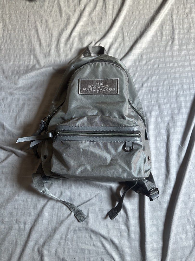 Marc Jacobs The Backpack Grey Nylon (Category: Backpacks) located in Quezon City. Submitted by stre3tw3ar (Listing ID 1468935539, Image 1). Description: - Brand/Model: Marc Jacobs Grey Nylon "The Backpack" - Exterior: Zippered front pocket with branded straps and dark metal hardware - Straps: Adjustable shoulder straps with logo webbing - Condition: Clean fabric inside and out; minor cracking on strap adjuster coating, structure holds solid - Siz
