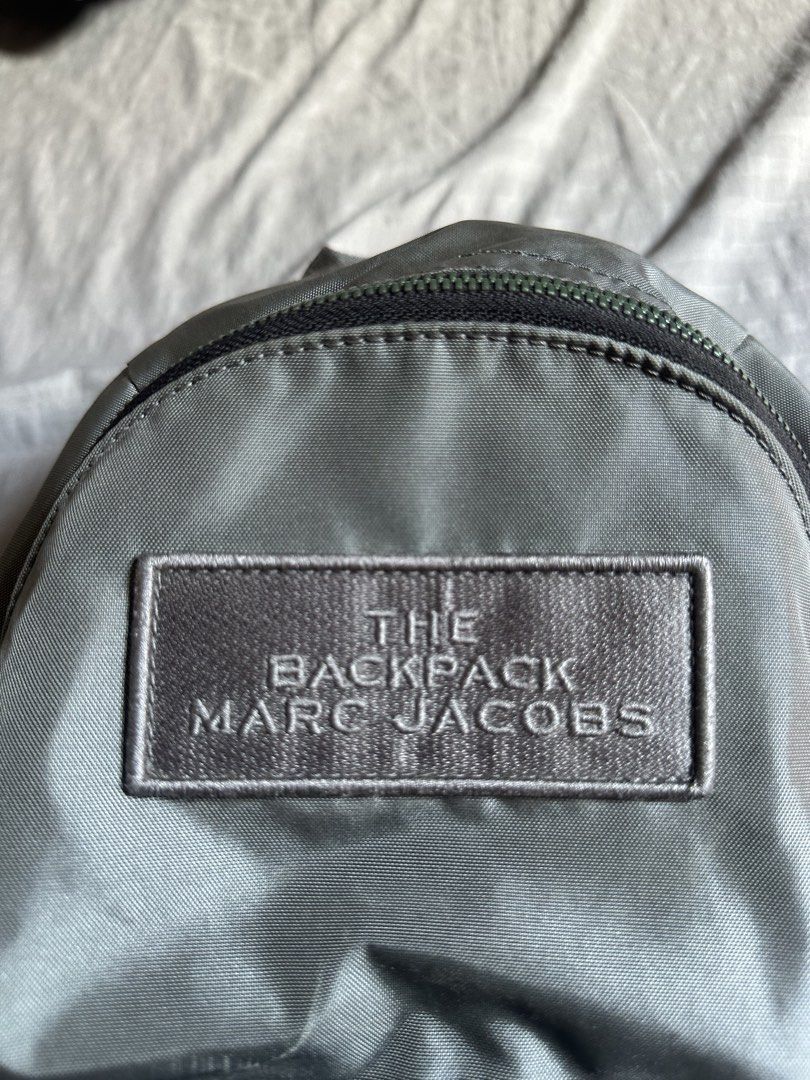 Marc Jacobs The Backpack Grey Nylon (Category: Backpacks) located in Quezon City. Submitted by stre3tw3ar (Listing ID 1468935539, Image 3). Description: - Brand/Model: Marc Jacobs Grey Nylon "The Backpack" - Exterior: Zippered front pocket with branded straps and dark metal hardware - Straps: Adjustable shoulder straps with logo webbing - Condition: Clean fabric inside and out; minor cracking on strap adjuster coating, structure holds solid - Siz