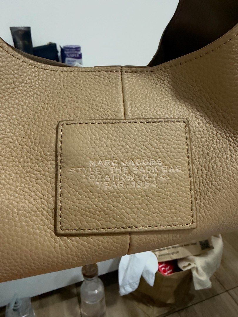 Marc Jacobs The Sack Bag Tan Leather (Category: Luxury Bags & Wallets) located in Manila. Submitted by ashfinds.mnl (Listing ID 1469145123, Image 3). Description: - Brand: Marc Jacobs - Almost brand new! Used once - Style: The Sack Bag - Material: Tan pebble leather with debossed lettering - Closure: Magnetic top handle design - Interior: Clean fabric lining with a zipper pocket - Inclusions: Original black and white print dust bag - Condition: E