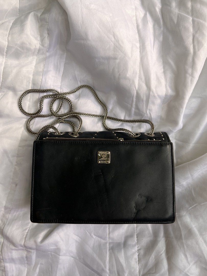 MCM Studded Black Leather Crossbody Bag (Category: Luxury Bags & Wallets) located in Quezon City. Submitted by rizza14ortiz (Listing ID 1468960632, Image 2). Description: Black leather crossbody bag from MCM. Silver tone studs in V patterns across the front. Silver chain strap attached through metal grommets. Back zipped pocket with metal plate displaying the MCM logo. Red leather interior lining with magnetic closure. Shows minor scratches on th