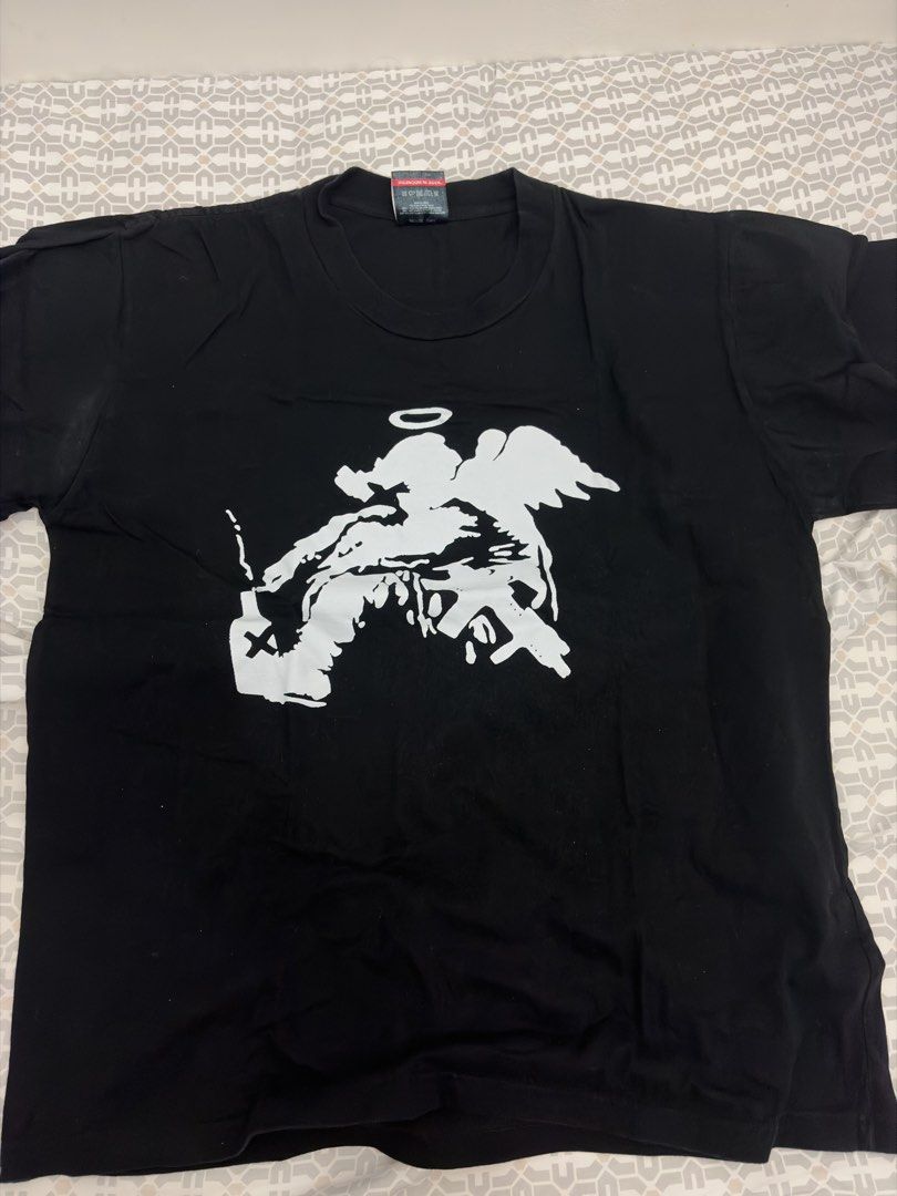 Mecoblast Graphic T-Shirt Large Black (Category: Tshirts & Polo Shirts ) located in Manila. Submitted by choufighter261 (Listing ID 1468942340, Image 1). Description: - Brand: Mecoblast - Size: Large - Color: Black (solid back) - Material: 100% cotton, made in Indonesia - Design: White graphic print on front featuring an angel motif holding a bottle and rifle - Details: Standard crew neck and short sleeves.