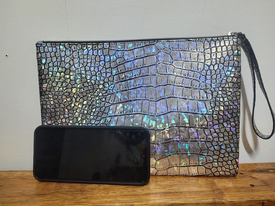 Metallic Holographic Crocodile Pattern Clutch Wristlet Bag (Category: Clutches) located in Pasig City. Submitted by healthnfeshn (Listing ID 1469005838, Image 3). Description: - Style: Silver metallic clutch with embossed crocodile pattern and rainbow iridescent shimmer - Closure: Secure top zipper - Convenience: Attached wrist strap on the right side - Capacity: Roomy interior fits your phone, keys, and cards - Occasion: Ideal for parties, night