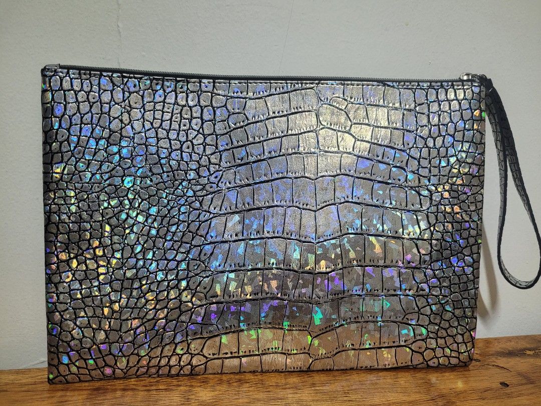 Metallic Holographic Crocodile Pattern Clutch Wristlet Bag (Category: Clutches) located in Pasig City. Submitted by healthnfeshn (Listing ID 1469005838, Image 1). Description: - Style: Silver metallic clutch with embossed crocodile pattern and rainbow iridescent shimmer - Closure: Secure top zipper - Convenience: Attached wrist strap on the right side - Capacity: Roomy interior fits your phone, keys, and cards - Occasion: Ideal for parties, night