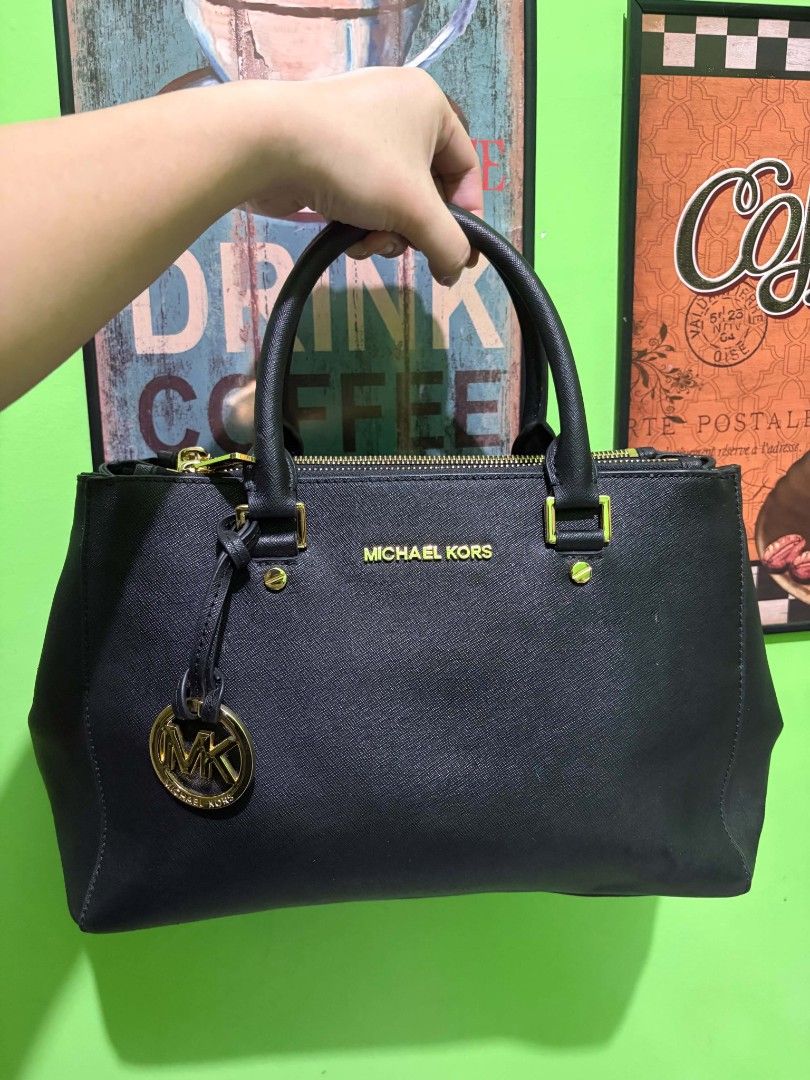 Michael Kors Black Leather Handbag with Gold Hardware (Category: Luxury Bags & Wallets) located in Manila. Submitted by niklaus_12345 (Listing ID 1468958972, Image 1). Description: - Brand: Michael Kors - Material: Premium Saffiano leather in classic black - Hardware: Elegant gold-tone accents - Features: Twin top handles and signature hanging MK charm - Closure: Secure top zip closure - Base: Metal protective feet - Interior: Spacious compartmen