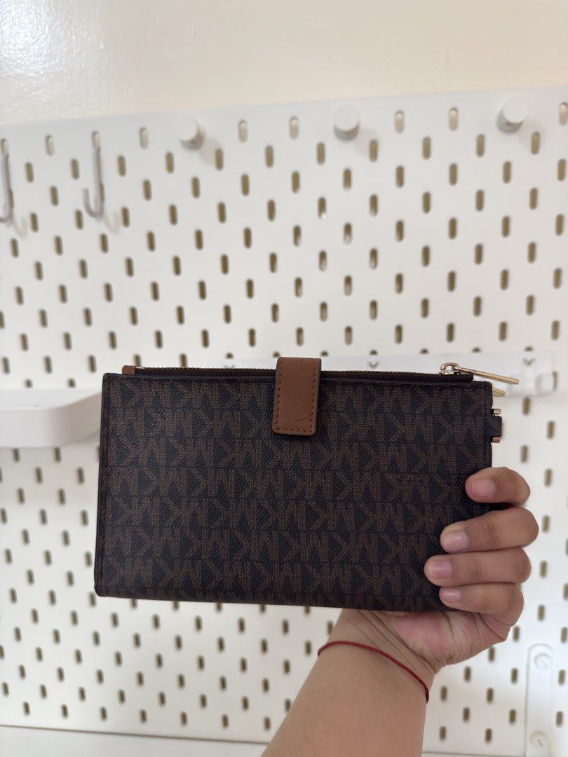 Michael Kors Brown Monogram Double Zip Wallet (Category: Luxury Bags & Wallets) located in Bacoor. Submitted by katie_tephanii (Listing ID 1468942355, Image 2). Description: - Not OG Michael Kors brown monogram wallet - Features double zip compartments with elegant gold hardware - Secure tan snap closure tab on the back - Organized interior with multiple card slots and cash compartments - Convenient side D-ring attached for charms or wristlets - 
