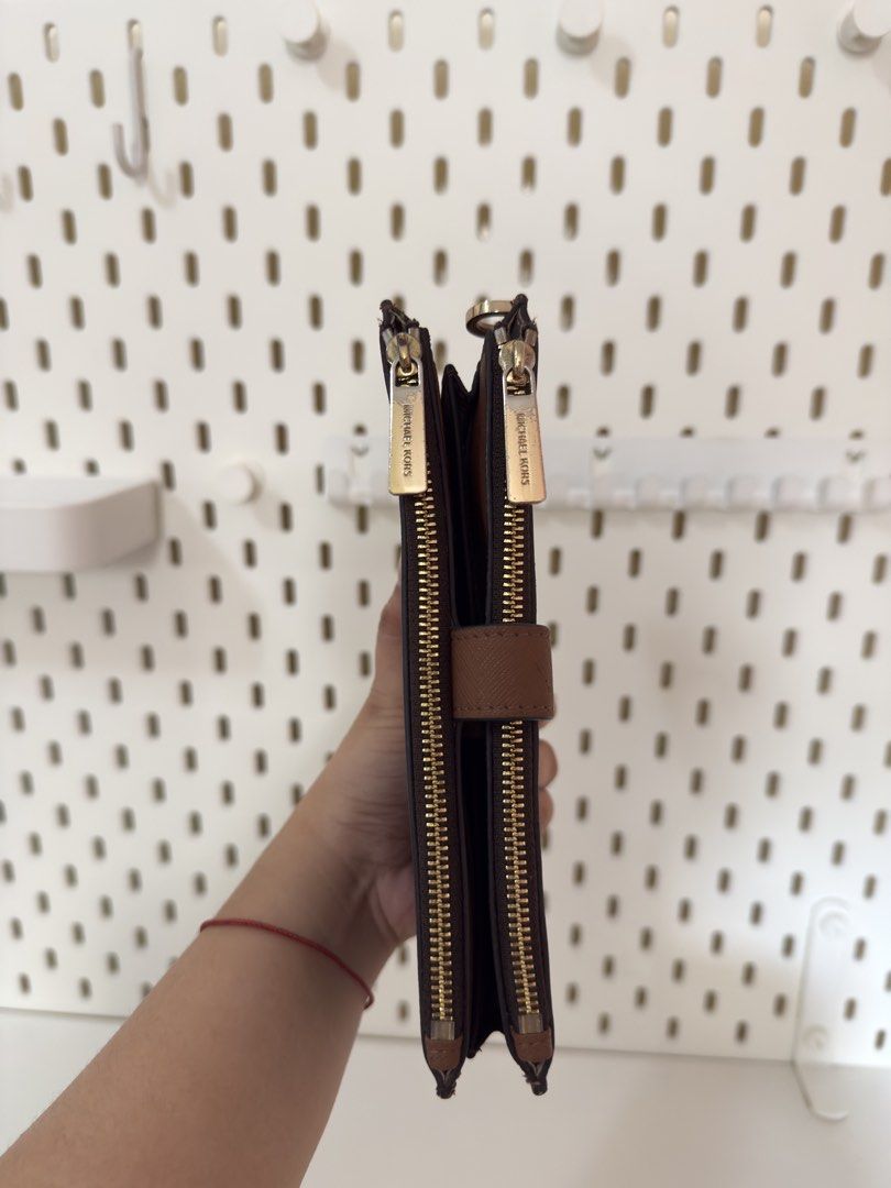 Michael Kors Brown Monogram Double Zip Wallet (Category: Luxury Bags & Wallets) located in Bacoor. Submitted by katie_tephanii (Listing ID 1468942355, Image 3). Description: - Not OG Michael Kors brown monogram wallet - Features double zip compartments with elegant gold hardware - Secure tan snap closure tab on the back - Organized interior with multiple card slots and cash compartments - Convenient side D-ring attached for charms or wristlets - 