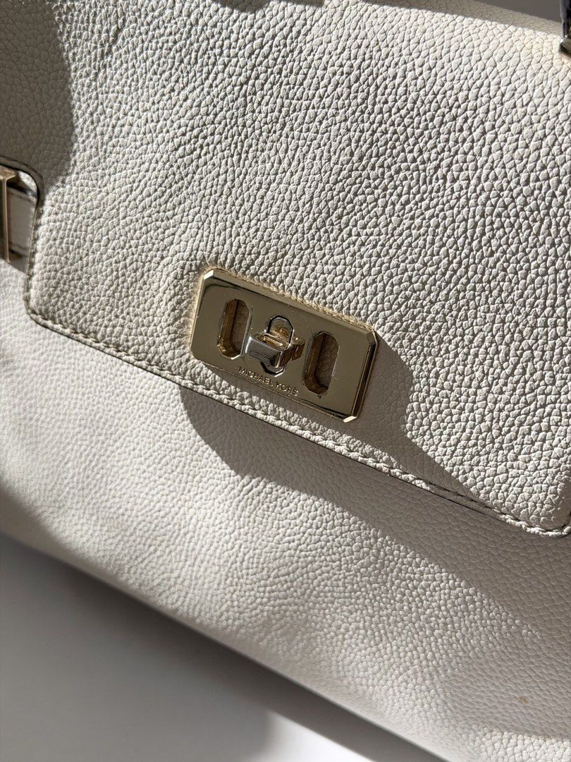 Michael Kors Karson Satchel White Handbag (Category: Luxury Bags & Wallets) located in Quezon City. Submitted by angelpadilla (Listing ID 1469029103, Image 2). Description: - Brand: Michael Kors Karson - Material: White pebble leather with gold-tone hardware - Closure: Signature turn-lock on front flap - Straps: Top handle and removable shoulder strap with logo charm - Condition: Shows minor signs of usage on leather and hardware, but still holds