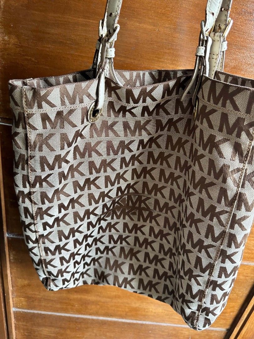 Michael Kors MK Monogram Tote Bag Brown Cream (Category: Luxury Bags & Wallets) located in Rizal. Submitted by mayra74 (Listing ID 1469094900, Image 2). Description: - Brand: Michael Kors - Design: Classic brown MK monogram print with cream leather trim - Hardware: Gold-tone, including hanging MK circle charm - Interior: Monogram-lined with 1 zip pocket and slip pockets - Straps: Adjustable double shoulder handles - Condition: Shows minor wear on