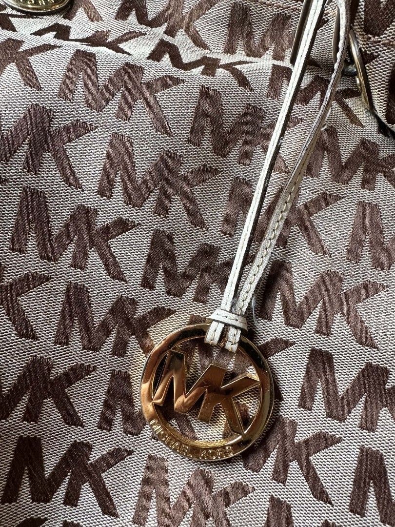 Michael Kors MK Monogram Tote Bag Brown Cream (Category: Luxury Bags & Wallets) located in Rizal. Submitted by mayra74 (Listing ID 1469094900, Image 3). Description: - Brand: Michael Kors - Design: Classic brown MK monogram print with cream leather trim - Hardware: Gold-tone, including hanging MK circle charm - Interior: Monogram-lined with 1 zip pocket and slip pockets - Straps: Adjustable double shoulder handles - Condition: Shows minor wear on
