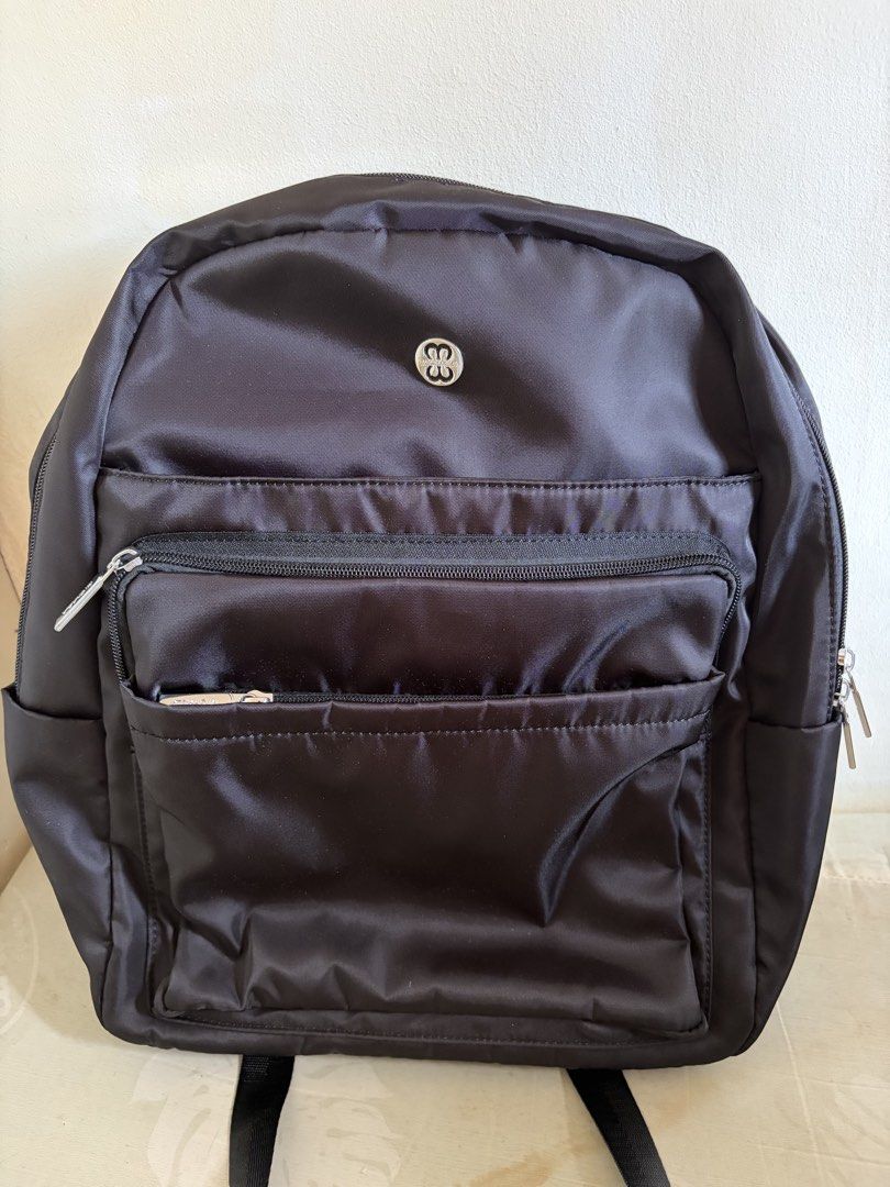 Michaela Black Nylon Backpack with Multiple Zipped Compartments (Category: Backpacks) located in Bacoor. Submitted by may_y. (Listing ID 1468933232, Image 1). Description: - Sleek black nylon backpack with a stylish shiny finish and chic silver hardware - Features a circular metallic logo patch on the top front - Spacious main compartment, middle zipped pocket, and a front horizontal pocket - Convenient side pockets on both sides for extra storag
