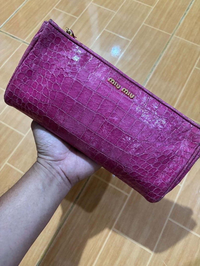 Miu Miu Pink Crocodile Embossed Clutch (Category: Clutches) located in Paranaque City. Submitted by poego (Listing ID 1468954115, Image 1). Description: - Brand: Miu Miu - Color: Bright pink - Material: Embossed crocodile pattern - Hardware: Gold tone with heart-shaped zipper charm - Features: Matching wrist strap and front lettering logo - Size: Compact and handy.