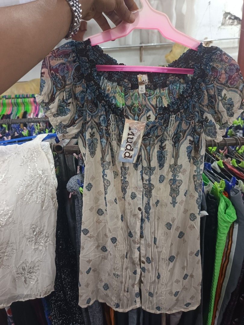 Mudd Boho Paisley Print Off-The-Shoulder Blouse (Category: Blouses) located in Tukuran. Submitted by coyythrift (Listing ID 1469073968, Image 2). Description: - Brand: Mudd (Tag still attached) - Size: Small - Design: Beige with blue, green, and brown paisley pattern - Style: Off-the-shoulder smocked neckline with short puff sleeves - Details: Button-down front with delicate lace trim - Fabric: Lightweight and comfortable.
