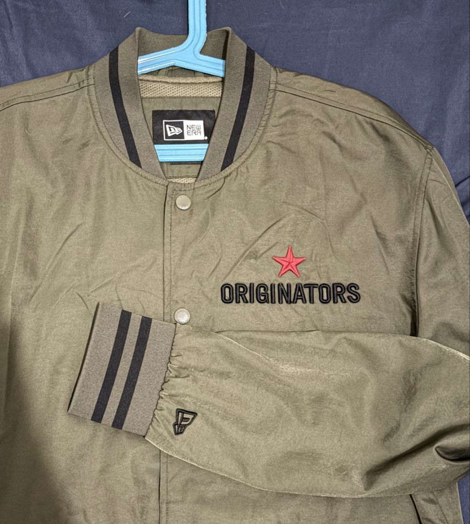 New Era Originators Olive Green Varsity Jacket Size Large (Category: Coats, Jackets and Outerwear) located in Manila. Submitted by nicosagm11t (Listing ID 1468997260, Image 3). Description: - Brand: New Era - Color: Olive Green - Size: Large 22x28 - Style: Varsity jacket with snap-button front closure - Details: Striped ribbed collar, cuffs, and hem - Embroidery: 'ORIGINATORS' lettering with red star on front, large 'NEW ERA' lettering on back - 