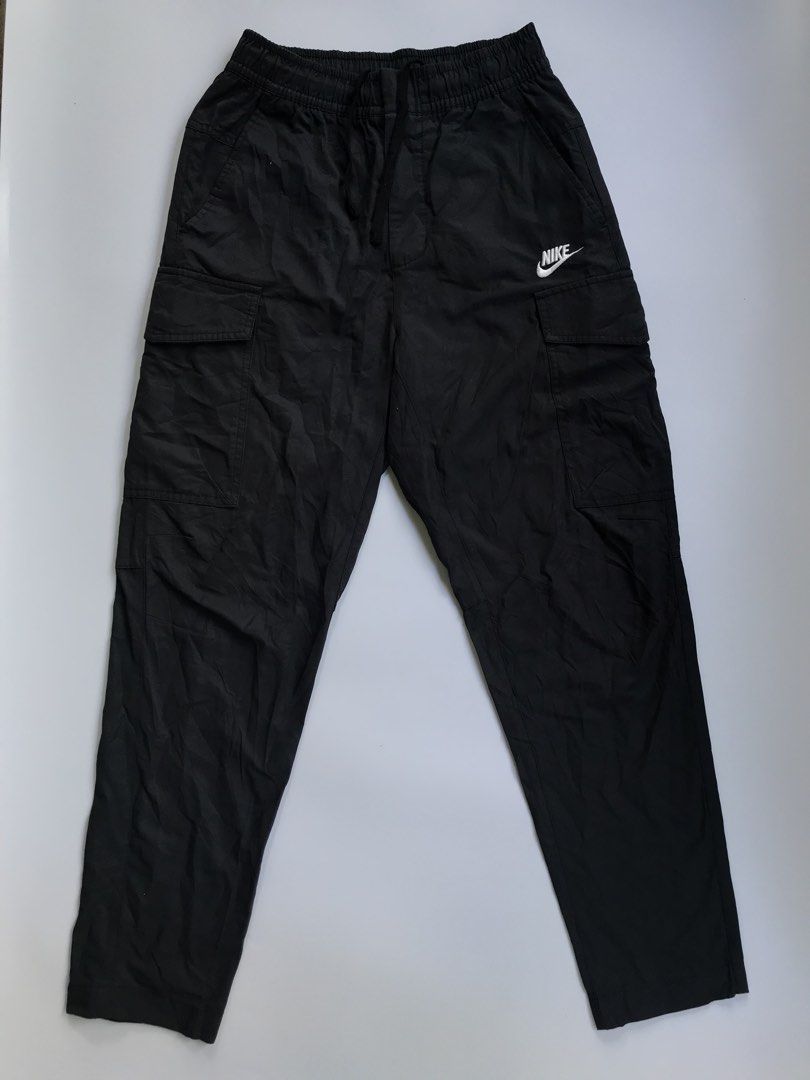 Nike Black Cargo Woven Pants Size S (Category: Joggers) located in Manila. Submitted by selme.finds (Listing ID 1468974658, Image 2). Description: - Brand: Nike - Color: Solid Black - Size: Small - Fit: Straight-leg with lightweight fabric construction - Waistband: Elastic with adjustable drawstring closure - Pockets: Multiple utility pockets on sides and back - Branding: White embroidered Nike logo on the left leg - Condition: Clean stitching th