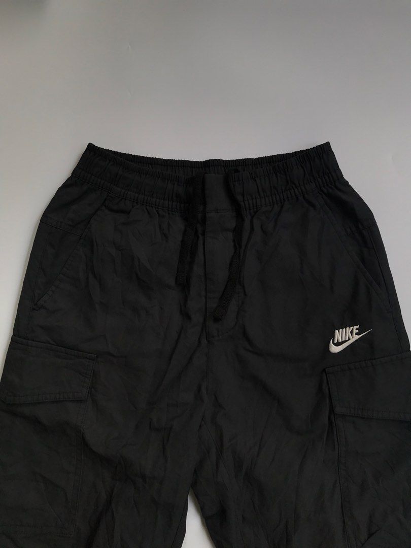 Nike Black Cargo Woven Pants Size S (Category: Joggers) located in Manila. Submitted by selme.finds (Listing ID 1468974658, Image 3). Description: - Brand: Nike - Color: Solid Black - Size: Small - Fit: Straight-leg with lightweight fabric construction - Waistband: Elastic with adjustable drawstring closure - Pockets: Multiple utility pockets on sides and back - Branding: White embroidered Nike logo on the left leg - Condition: Clean stitching th