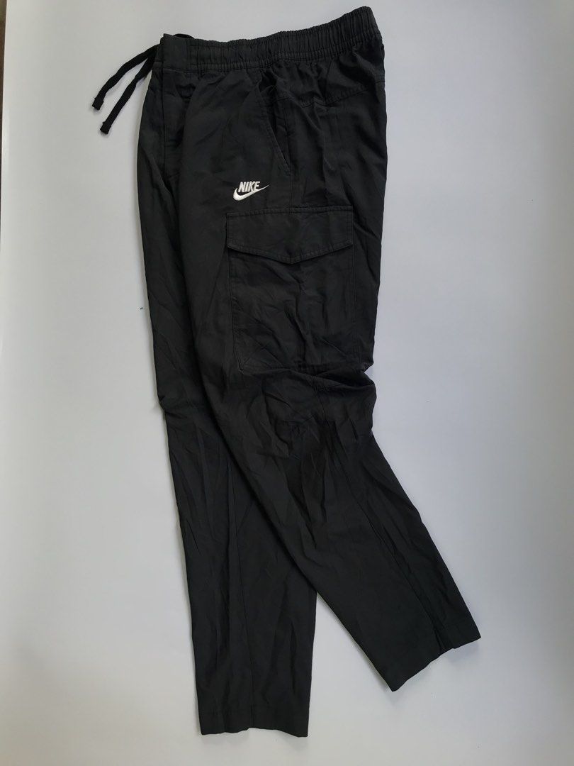 Nike Black Cargo Woven Pants Size S (Category: Joggers) located in Manila. Submitted by selme.finds (Listing ID 1468974658, Image 1). Description: - Brand: Nike - Color: Solid Black - Size: Small - Fit: Straight-leg with lightweight fabric construction - Waistband: Elastic with adjustable drawstring closure - Pockets: Multiple utility pockets on sides and back - Branding: White embroidered Nike logo on the left leg - Condition: Clean stitching th