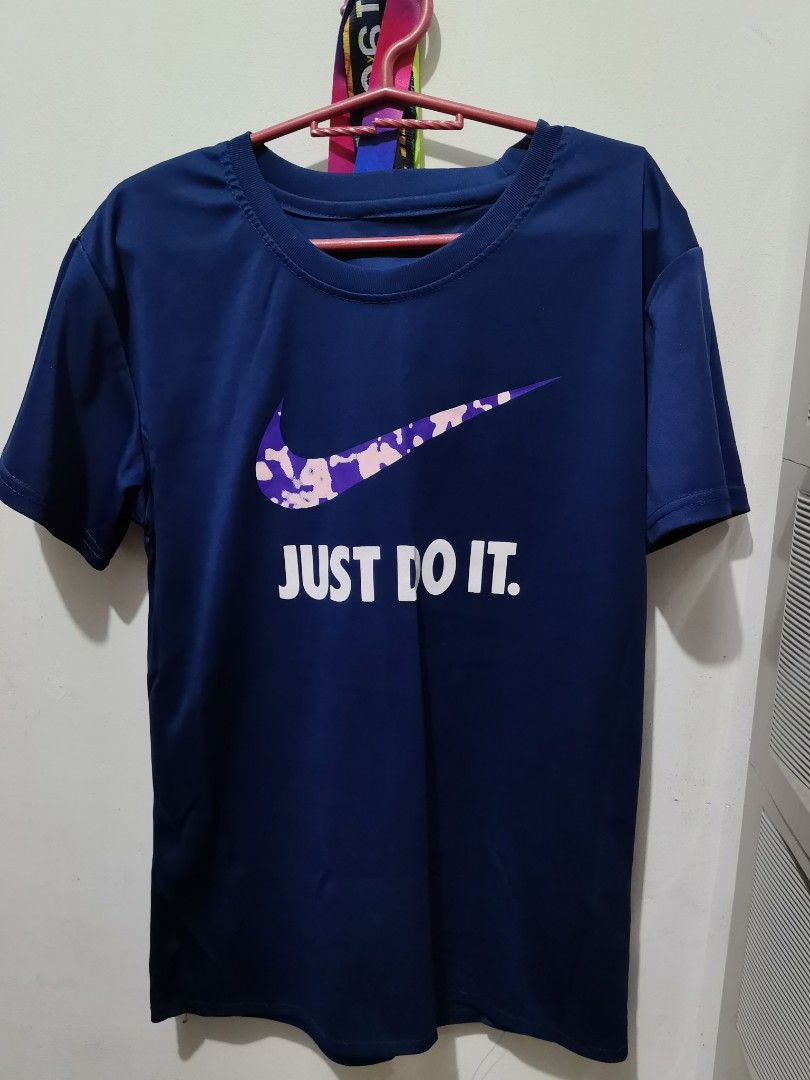 Nike Blue Just Do It T-Shirt (Category: Tshirts & Polo Shirts ) located in Valenzuela. Submitted by paaaatt (Listing ID 1469017069, Image 2). Description: Dark blue Nike t-shirt with short sleeves and a crew neck. Front graphic features a purple and pink camo swoosh above white text saying JUST DO IT. Back is plain solid dark blue. Soft athletic fabric..