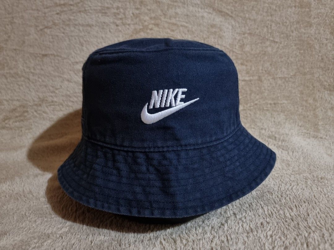 Nike Bucket Hat Mens (Category: Caps & Hats) located in Imus. Submitted by aim_for_less (Listing ID 1469021098, Image 1). Description: Nike Bucket Hat Mens - Brand: Nike - SIZE: M/L (58-60cm) - Color: Dark blue with a washed look and white embroidered logo - Features: Breathable mesh back panel with a built-in zipper pocket - Material: Sturdy and durable - Fit: Standard adult size, comfortable fit - Condition: Clean and ready to wear for outdoor 