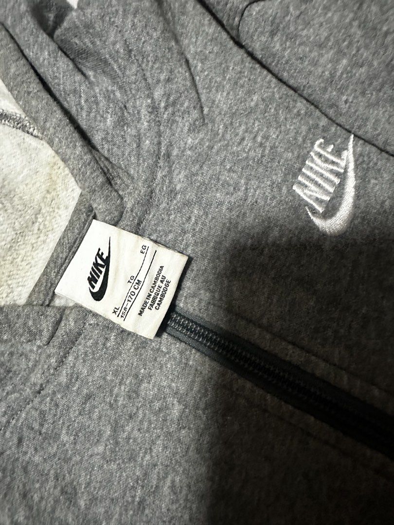 Nike Grey Zip-Up Hoodie (Category: Hoodies) located in Baybay. Submitted by comicowl (Listing ID 1469102010, Image 2). Description: - Brand: Nike - Color: Grey with white embroidered logo - Style: Zip-up hoodie with split kangaroo pockets - Material: Comfortable cotton blend - Fit/Details: Ribbed cuffs and hem, attached hood (drawstrings missing) - Condition: Great everyday casual staple.